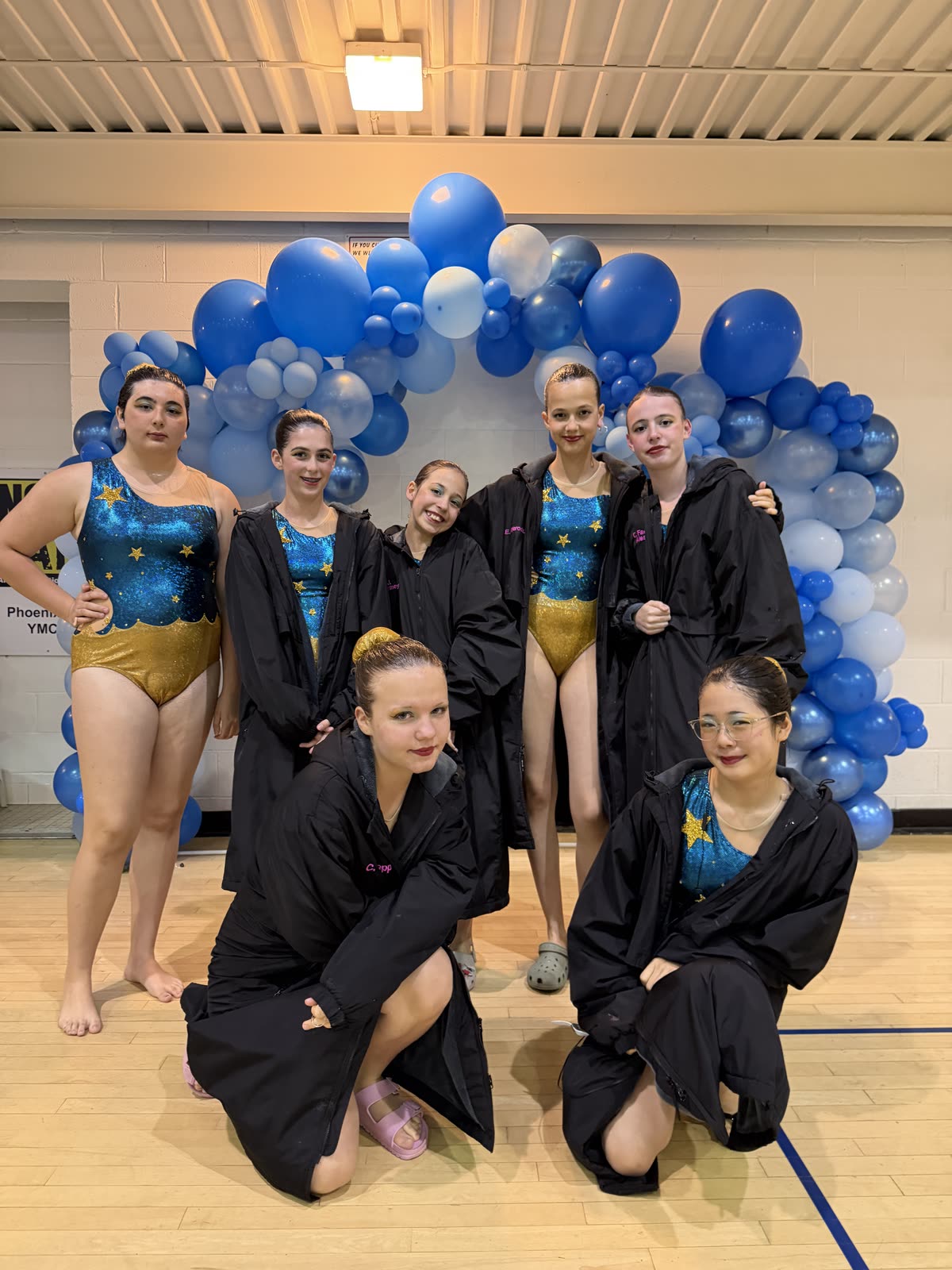 Imagine Synchro swimmers together at a meet in team parkas over their competition suits