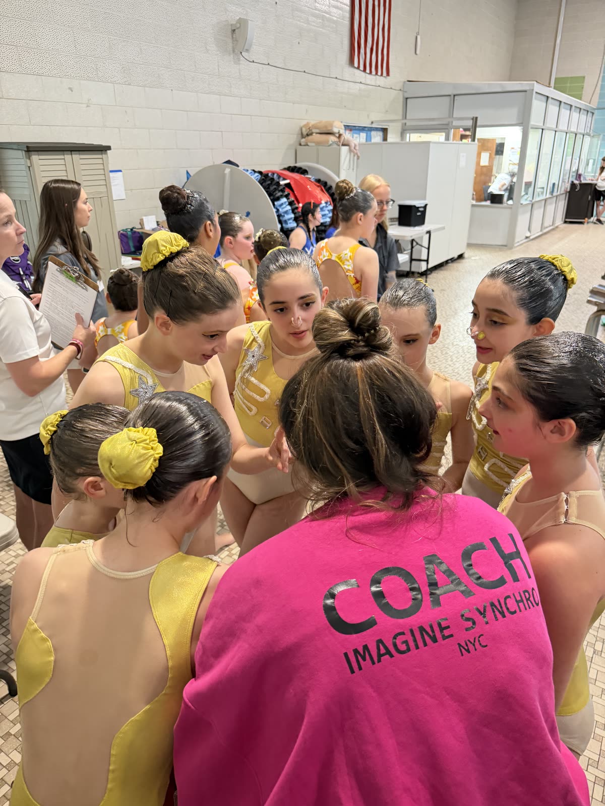 A coach in an Imagine Synchro jacket talking the team through a routine before they swim